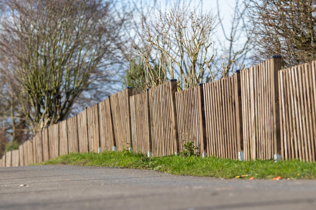 Clôture en bois dans un jardin sous un ciel bleu, exemple de clôture posée par C.N.E dans le Calvados